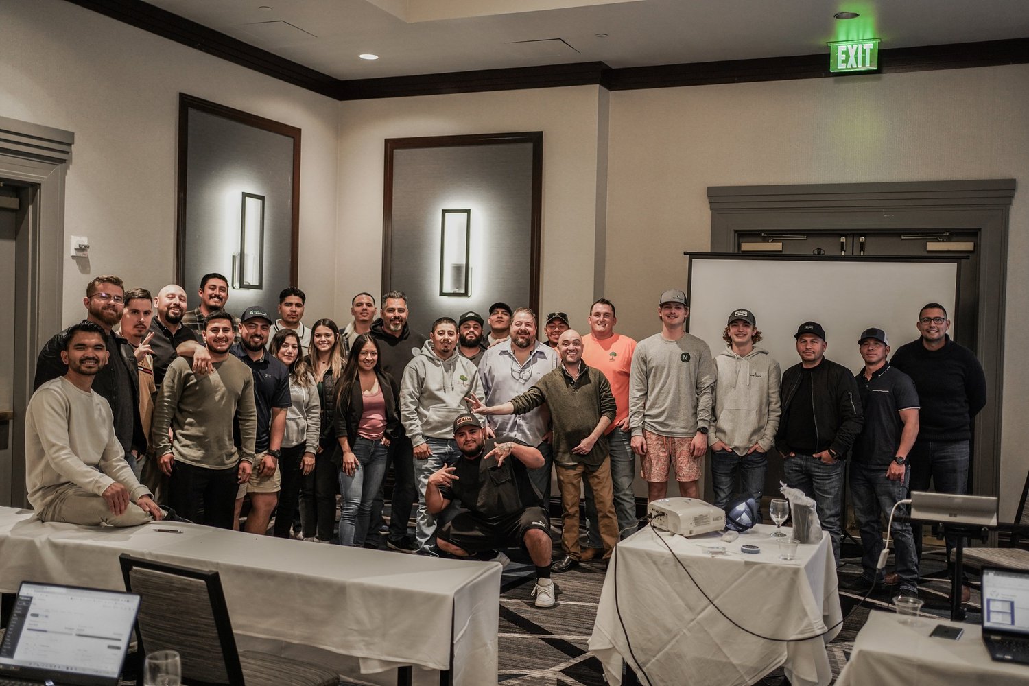 Group of people posing for a photo in a conference room with tables and laptops.